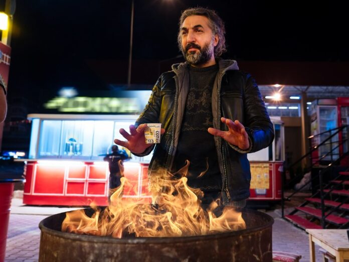 Man warming hands over an oil drum fire