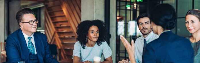 Professionals sitting at boardroom table with corporate lawyer to evaluate outside counsel 