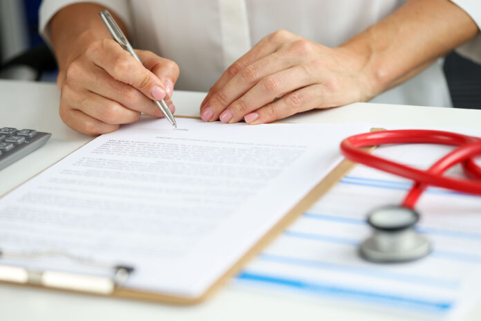 A close-up photo of a person writing on a clipboard.