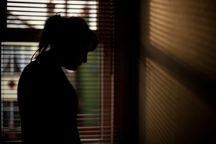 The silhouette of a woman standing by a window.