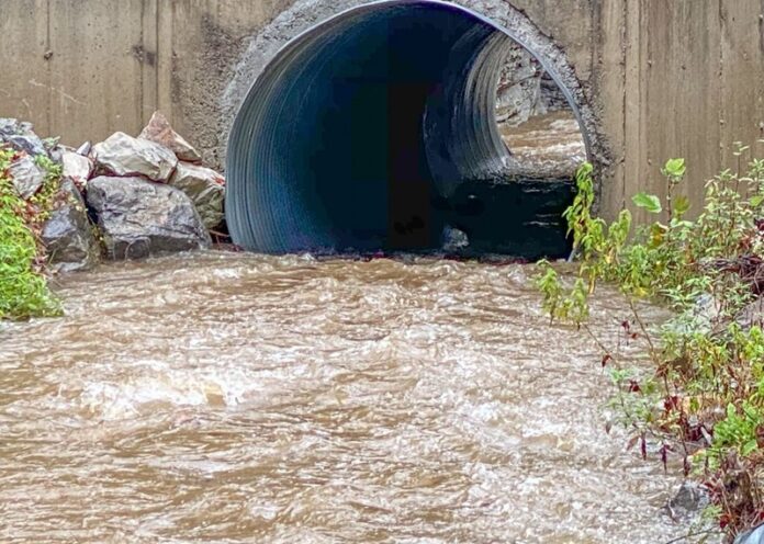 Water flowing through a large storm drain after rainfall caused extreme flooding.