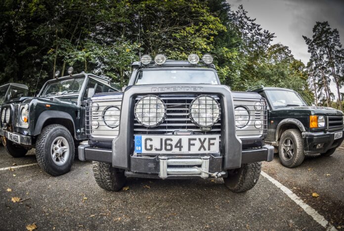 Close up of Land Rover Defender with other Land Rovers in the background